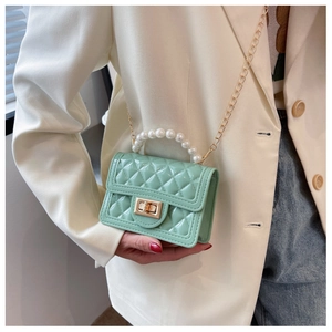 Detail of mint green quilted silicone mini bag with pearl handle and golden chain strap