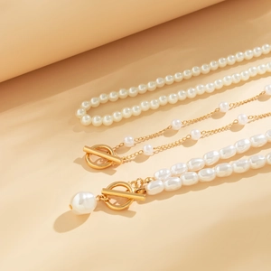 Detailed view of layered pearl necklaces featuring gold T-bars and baroque pendants
