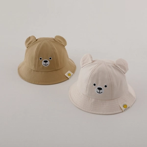 Détail de chapeaux bobs pour bébés en beige et kaki avec oreilles d'ours et broderie