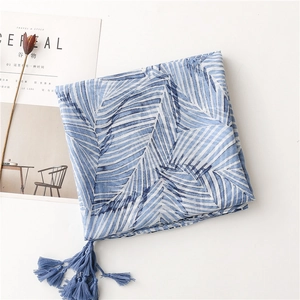 Detail of blue palm leaf print scarf with handcrafted tassels and boho aesthetic