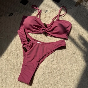 Detail of ribbed purple bikini with tortoiseshell beads on plush carpet background