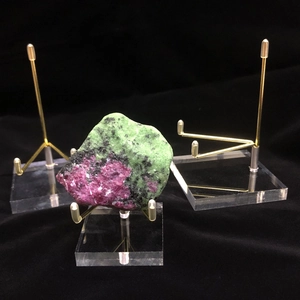 Clear acrylic and gold metal stand displaying a red and green mineral specimen