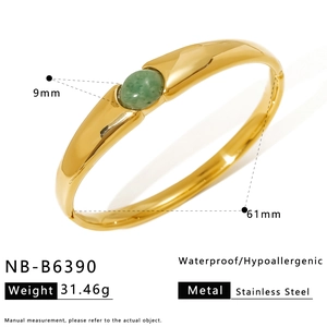 Detail view of gold stainless steel bangle with a 9mm green oval stone and H-letter design