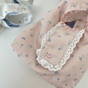 Dettaglio della borsa in tela floreale rosa con bordo in pizzo bianco e fodera a quadretti