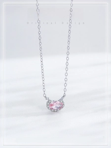 Macro detail of pink oval gemstone pendant with white diamond border on silver necklace