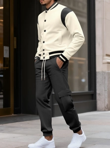 Dettaglio della giacca baseball crema e nera e dei pantaloni cargo da uomo stile urbano