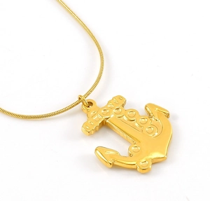 Macro detail of a golden anchor pendant featuring a classic nautical design and snake chain