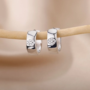 Detailed macro of silver U-shaped hoop earrings with sparkling zircon eye pattern