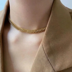 Golden flat braided choker necklace in stainless steel shown on model with brown blazer