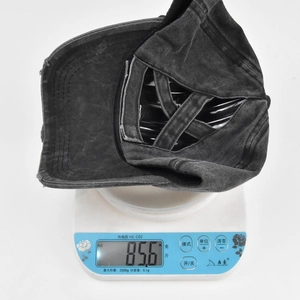 Black distressed ponytail baseball hat showing 85.6g weight on a digital scale