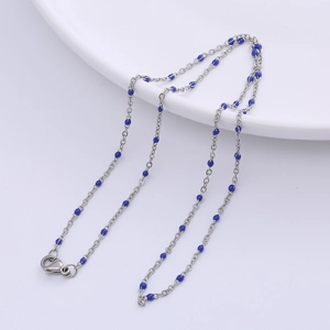 Silver O-chain necklace with blue circular beads and lobster clasp on white ceramic