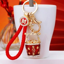 Detail of red braided keychain with diamond-encrusted Kirin and golden ingots