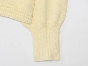 Close-up of soft ribbed cuffs and pale yellow knit texture on long sleeve cardigan