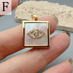 Detailed macro view of square gold pendant with white shell and inlaid evil eye motif