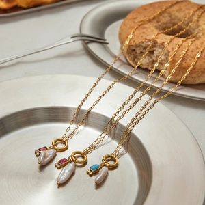 Detailed shot of gold necklaces with irregular pearls and rectangle gemstone pendants