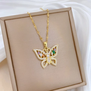 Close-up of a luxury gold butterfly pendant with colorful zircons on a white silk backdrop