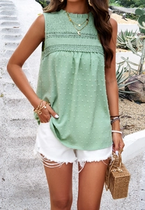 Detail of green sleeveless top featuring textured dots and elegant lace patchwork design