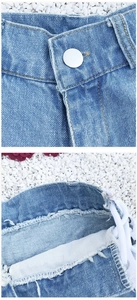 Dettaglio degli shorts di jeans a vita alta con bottoni metallici e lacci laterali