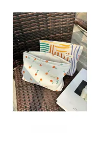 Close-up of floral corduroy makeup bag with metal zipper on a rustic rattan chair