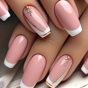 Pink and white French press-on nails with golden leaf accents and metallic trim details