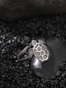Macro shot of a silver turtle ring with white inlay on a dark natural stone base