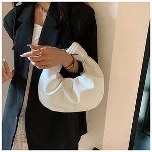Close-up of a white pleated cloud bag with handle knot detail on a model's arm