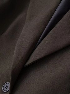 Detailed macro view of dark brown suit fabric with sleek lining and resin button