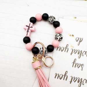 Detail of pink and black silicone bead keychain with leopard print and Jesus cross