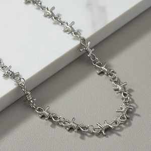 Silver industrial punk barbed wire style necklace for men and women on marble background