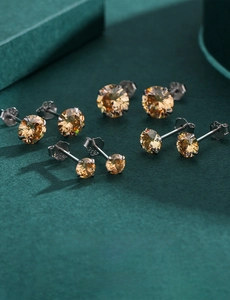Macro view of S925 sterling silver studs with champagne zircon stones on green velvet