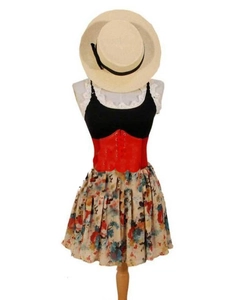 Detail of red wide elastic corset belt styled over a black top and floral mini skirt