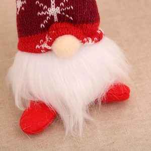 Detail of red knit hat with snowflakes and white plush beard on Christmas gnome