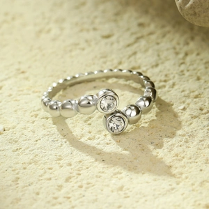 Silver bead band open ring with dual clear zircon accents on a stone background