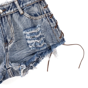 Detailansicht blauer Denim-Shorts mit seitlicher Schnürung und ausgefransten Saumkanten