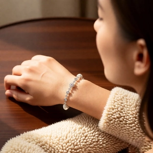 Close-up of pearl bracelet with star zircon charms on woman's wrist with soft knitwear