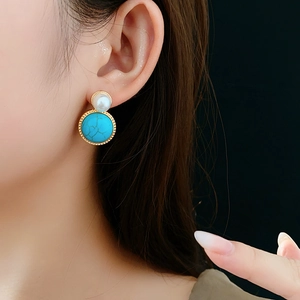 Detail of vintage round pearl and green turquoise drop earrings on a model's ear