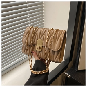 Detail view of khaki quilted chain bag with wavy texture and gold metal lock