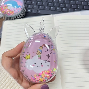 Close-up of egg-shaped unicorn hairbrush with pink glitter and cartoon patterns