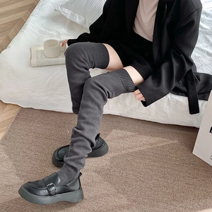 Detailed texture of dark grey ribbed knit over-the-knee socks paired with platform shoes