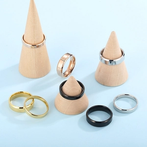 Polished stainless steel rings in gold, silver, black, and rose gold on wooden stands