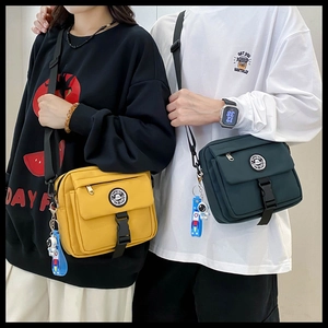 Detail of canvas messenger bags in yellow and green with astronaut charms for couples