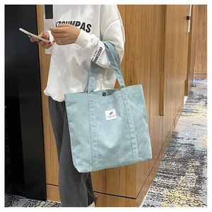 Detail of light blue corduroy tote bag showing ribbed texture and button closure