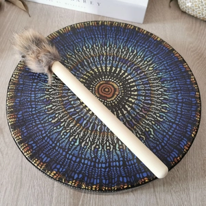 Colorful festive hand drum with mandala pattern and wood mallet on a wooden surface