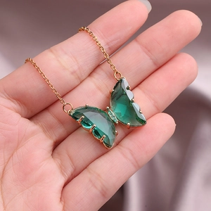 Rose gold stainless steel necklace featuring a green crystal butterfly pendant in a hand
