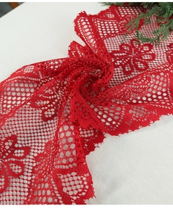 Close-up of red Christmas lace table runner with intricate floral patterns and scalloped edges