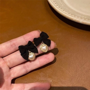 Détail de boucles d'oreilles nœud vintage avec perles en forme de cœur et tissu noir