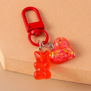 Detail of red gummy bear keychain with heart pendant and metallic lobster clasp on soft base