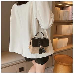 Detail of a straw patchwork crossbody bag with black leather flap and stylish double tassels