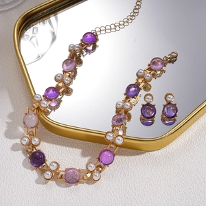 Vintage style jewelry set with purple gemstones and pearls on a gold mirrored tray