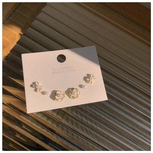 Detailed close-up of vintage pearl and camellia stud earring set on elegant display card